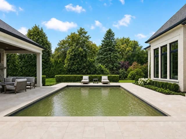 A backyard swimming pool with cloudy green water in a listing photo